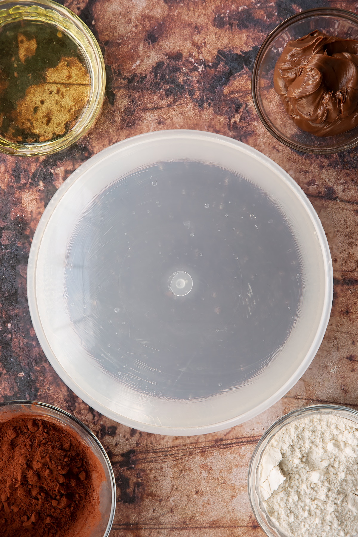 Nutella pudding cake batter in a greased cake dish with a lid on top.