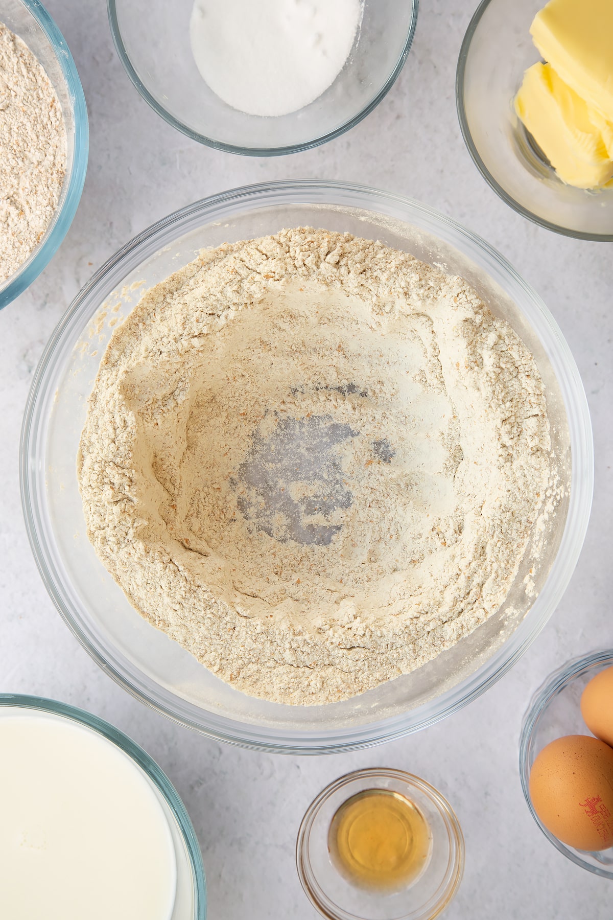 wholemeal flour and sugar in a large clear bowl with a hole in the middle of the dry mixture.
