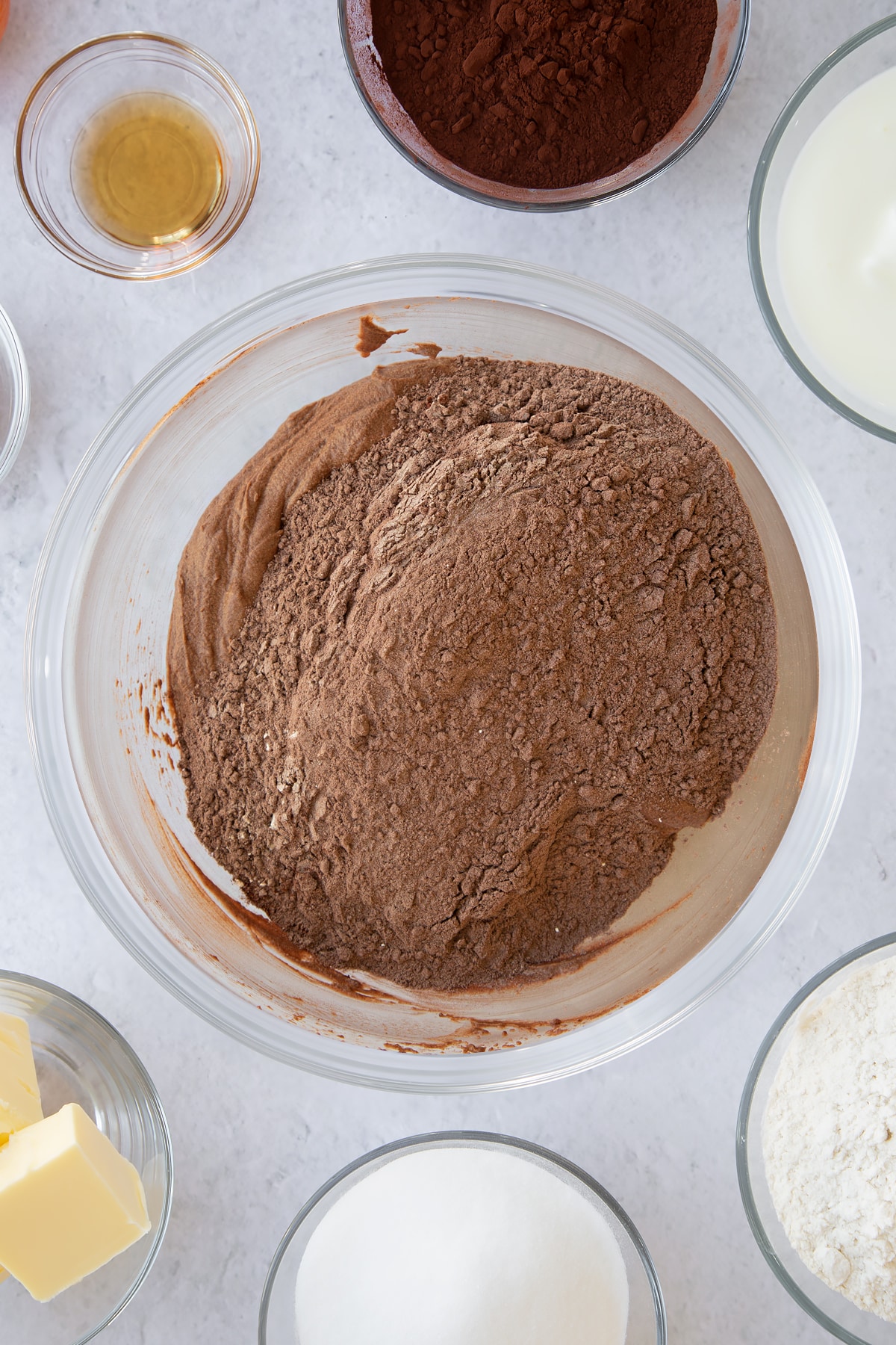 whisked buttermilk and sugar mix in a large clear bowl to create a batter topped with cocoa flour mix.