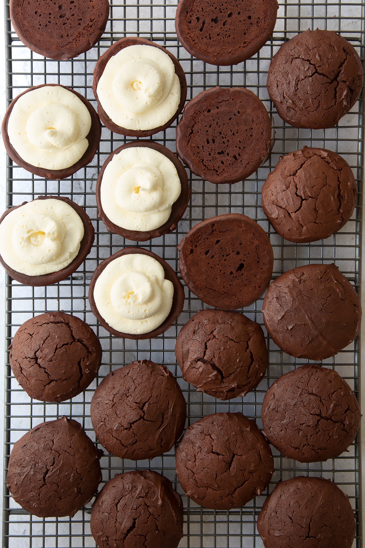 chocolate whoopie pie cookies turned over on a wire cooling rack with half topped with buttercream filling.