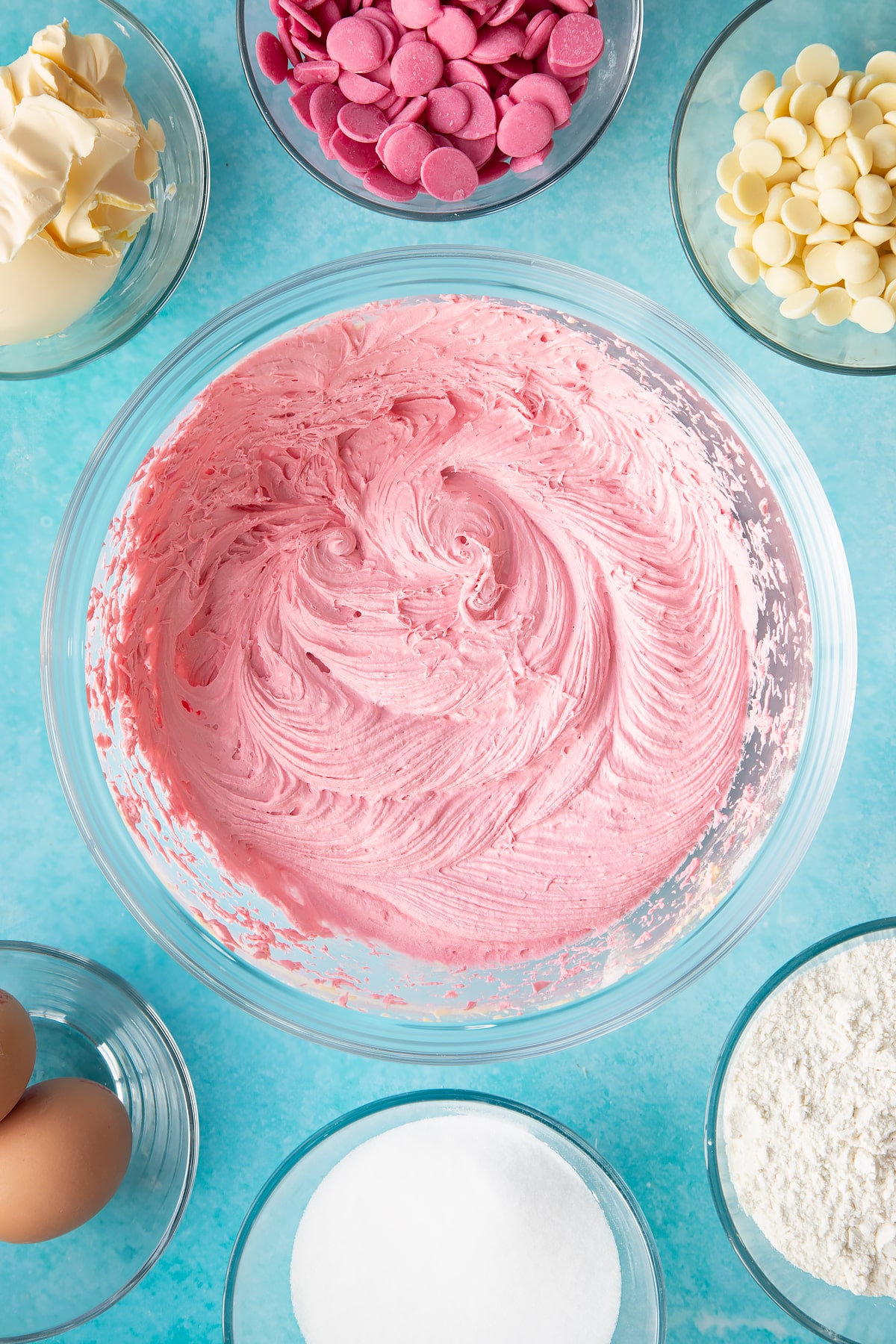 whisked pink cupcake mixture in a large clear bowl.
