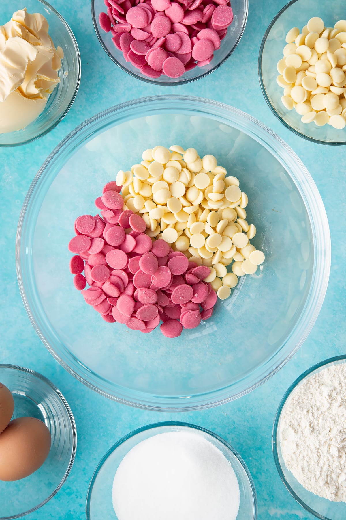 pink candy melts and white chocolate chips in a large clear bowl.