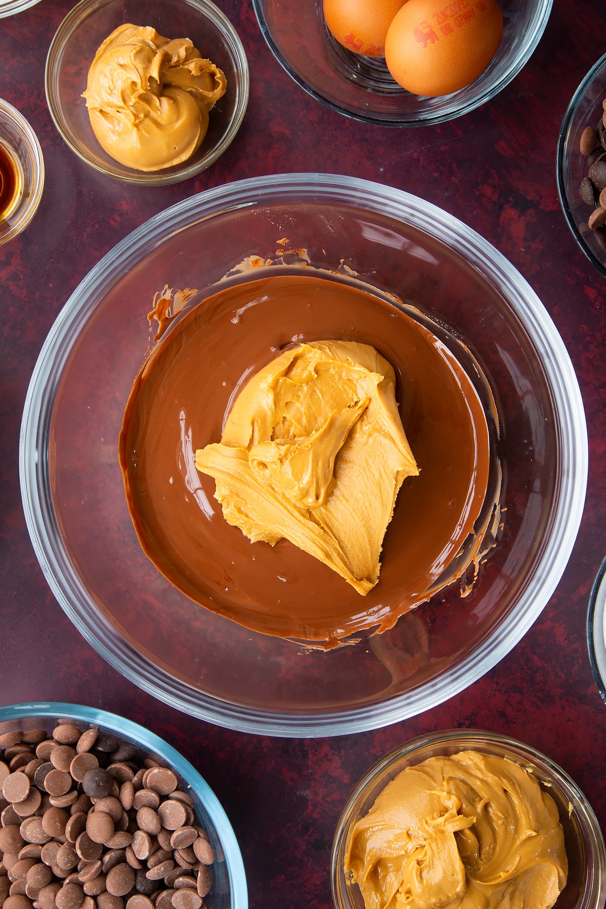 melted milk and dark chocolate chips in a large clear bowl topped with peanut butter.