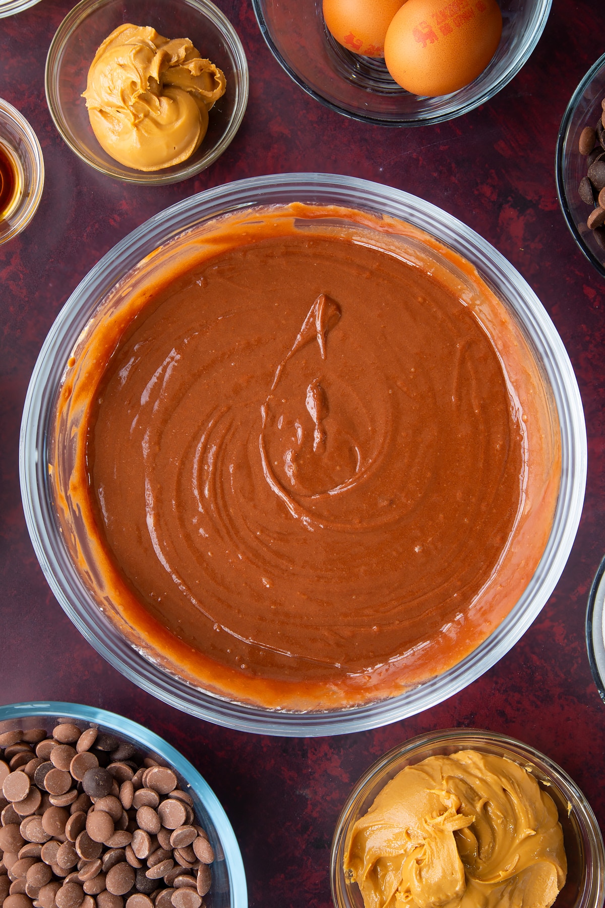 eggs, buttermilk, vanilla, butter and sugar mixed with the chocolate peanut butter mixture in a clear bowl.