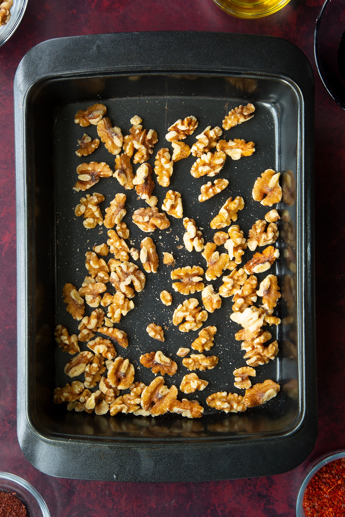 whole walnuts spread into an even layer in the base of a baking tray.