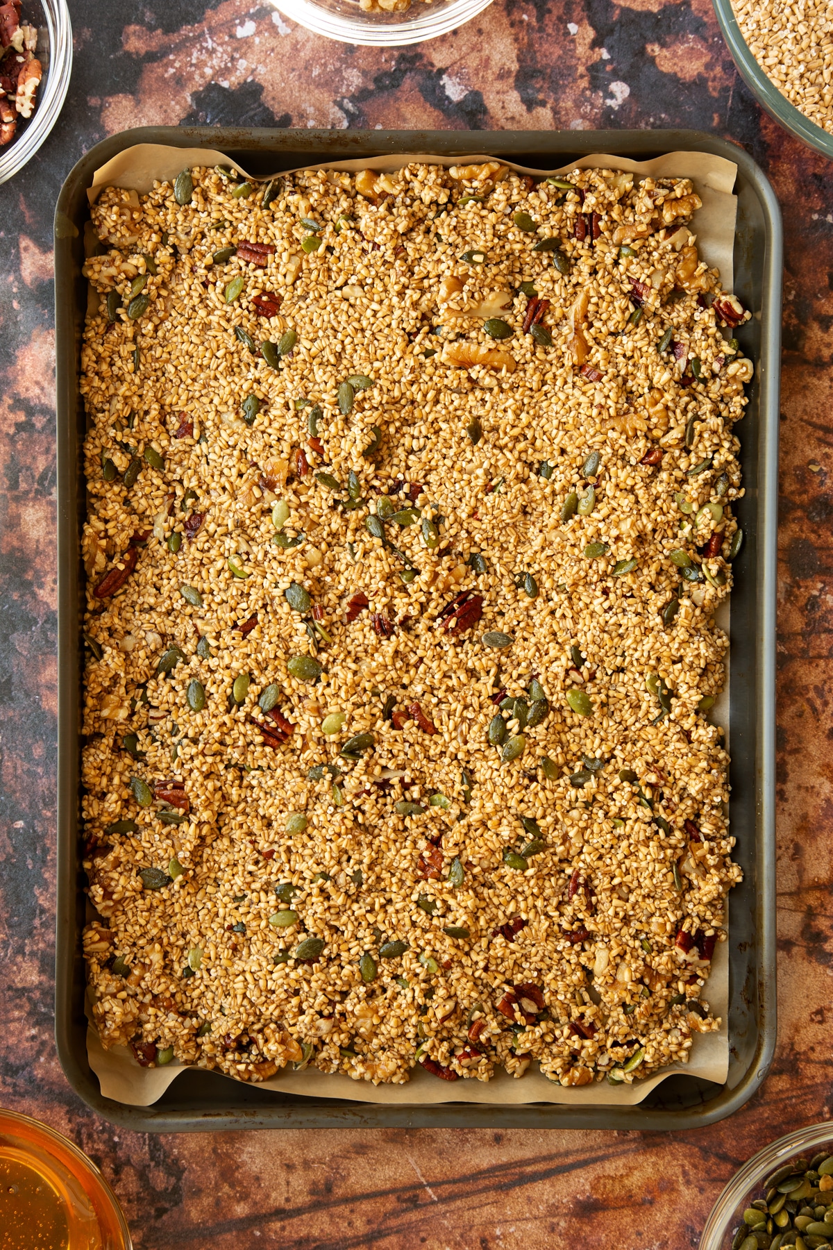 Steel cut oats mixture laid out on a baking tray lined with baking paper.
