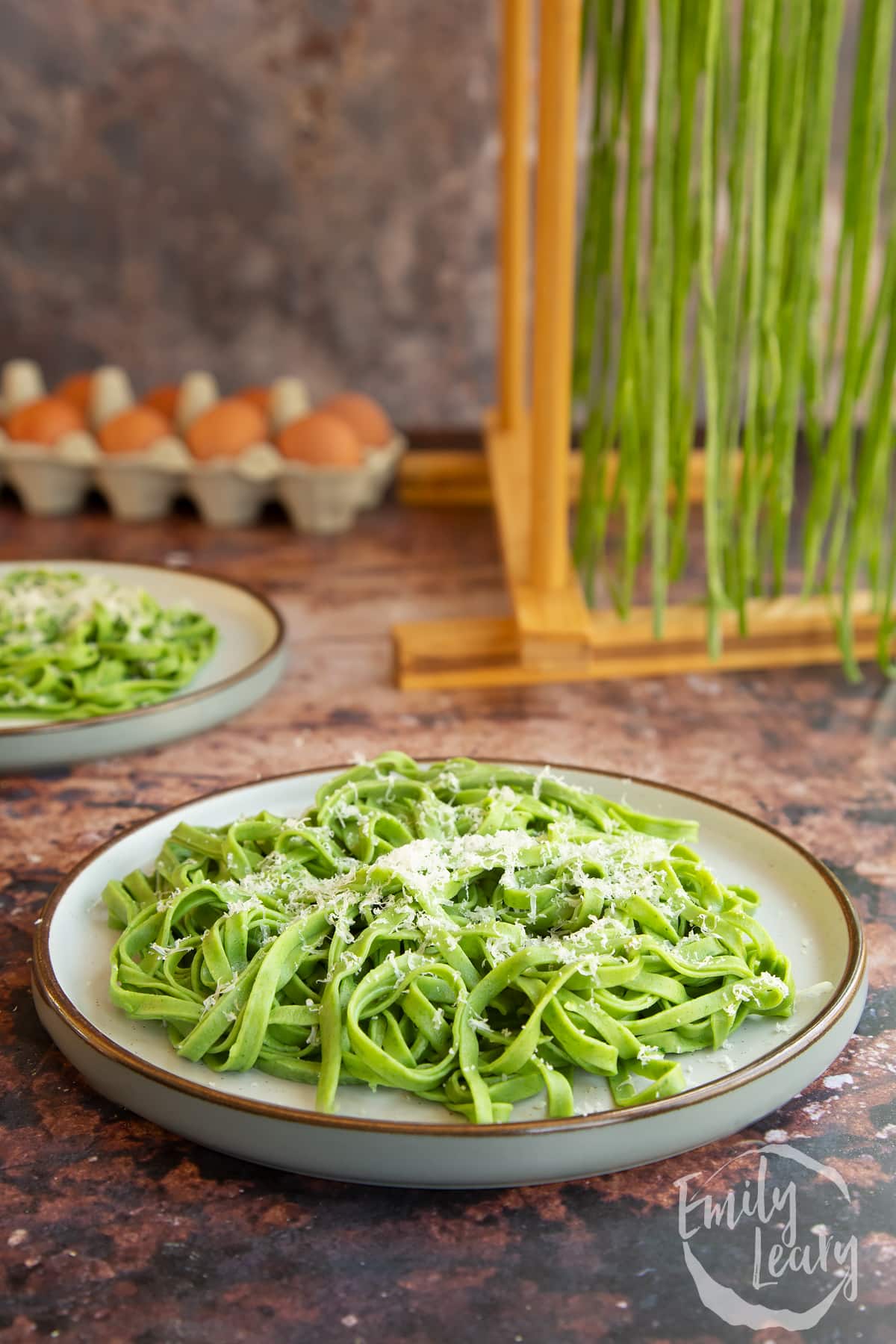 Tagliatelle verdi on a white plate topped with grated cheese.