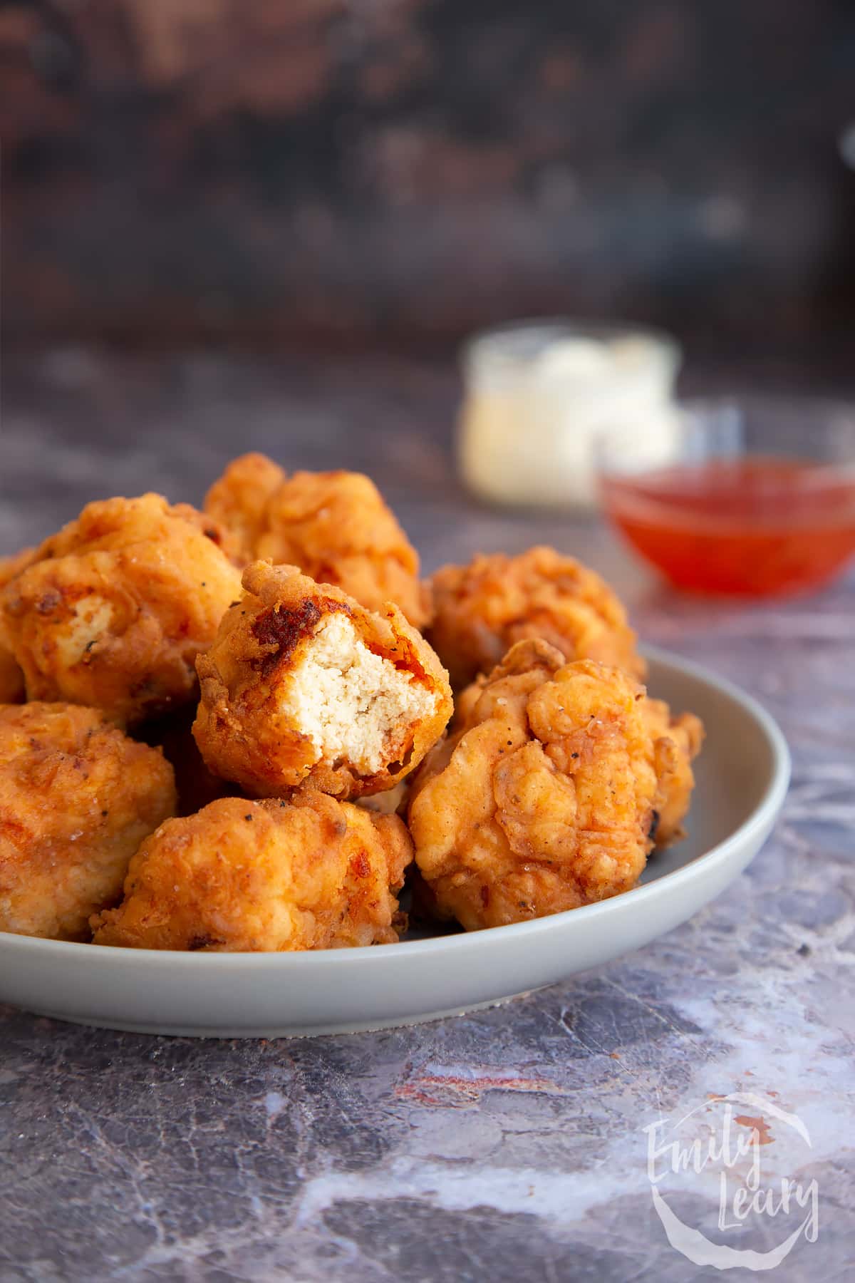 a half eaten piece of buttermilk fried tofu on top of a plate full of buttermilk fried tofu.