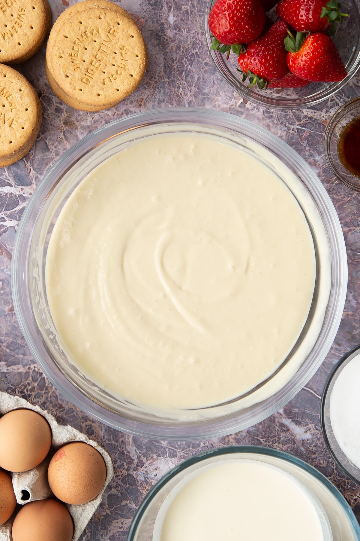 whisked cream cheese, double cream, eggs, flour, sugar mix in a large clear bowl.