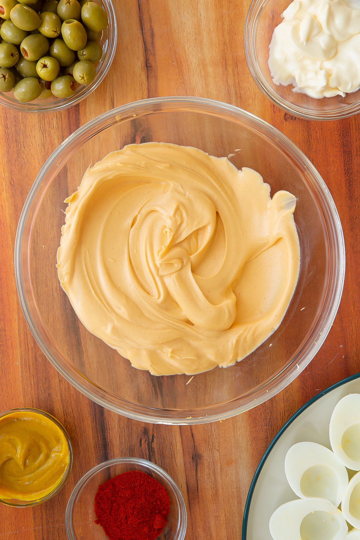 Mixing together the mayonnaise, smoked paprika and egg yolks together in a clear glass bowl.