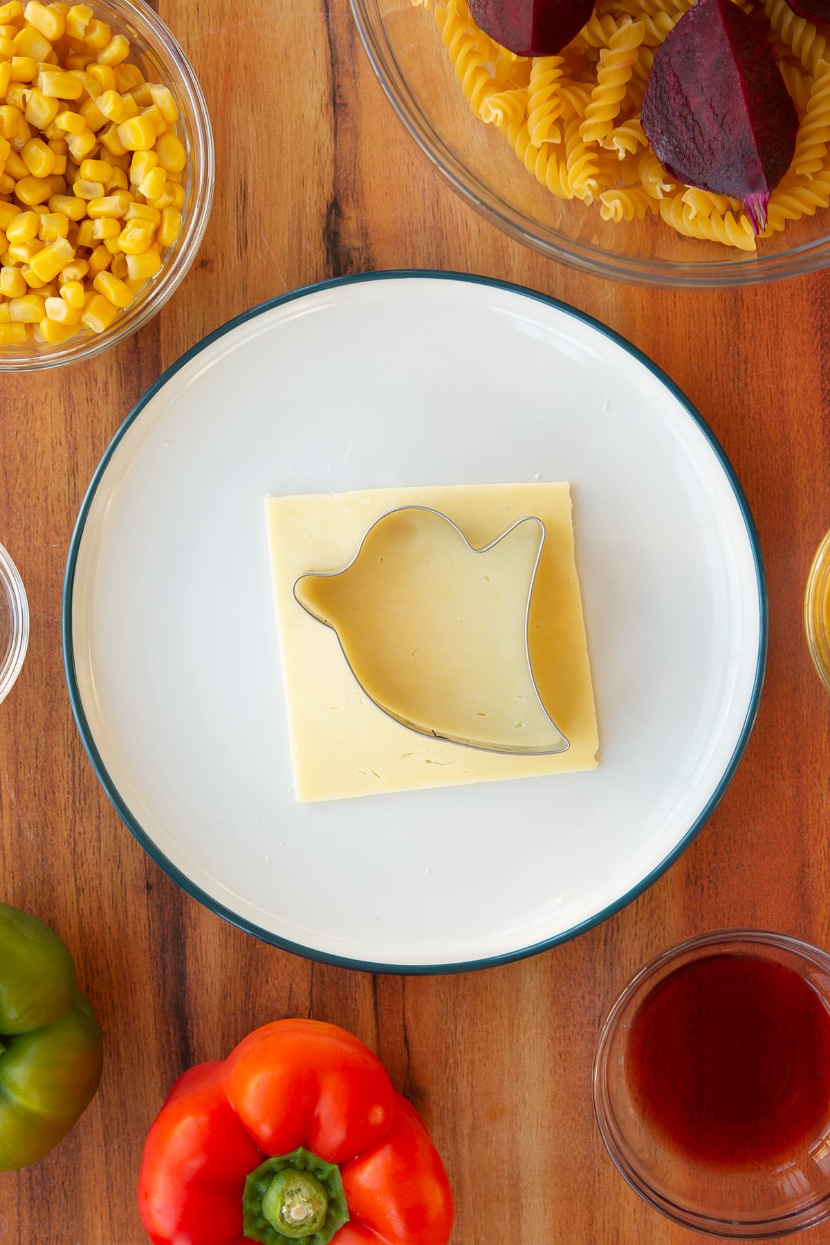Overhead shot of a cookie cutter being used on slices of cheese to cut out the outline of a ghost.