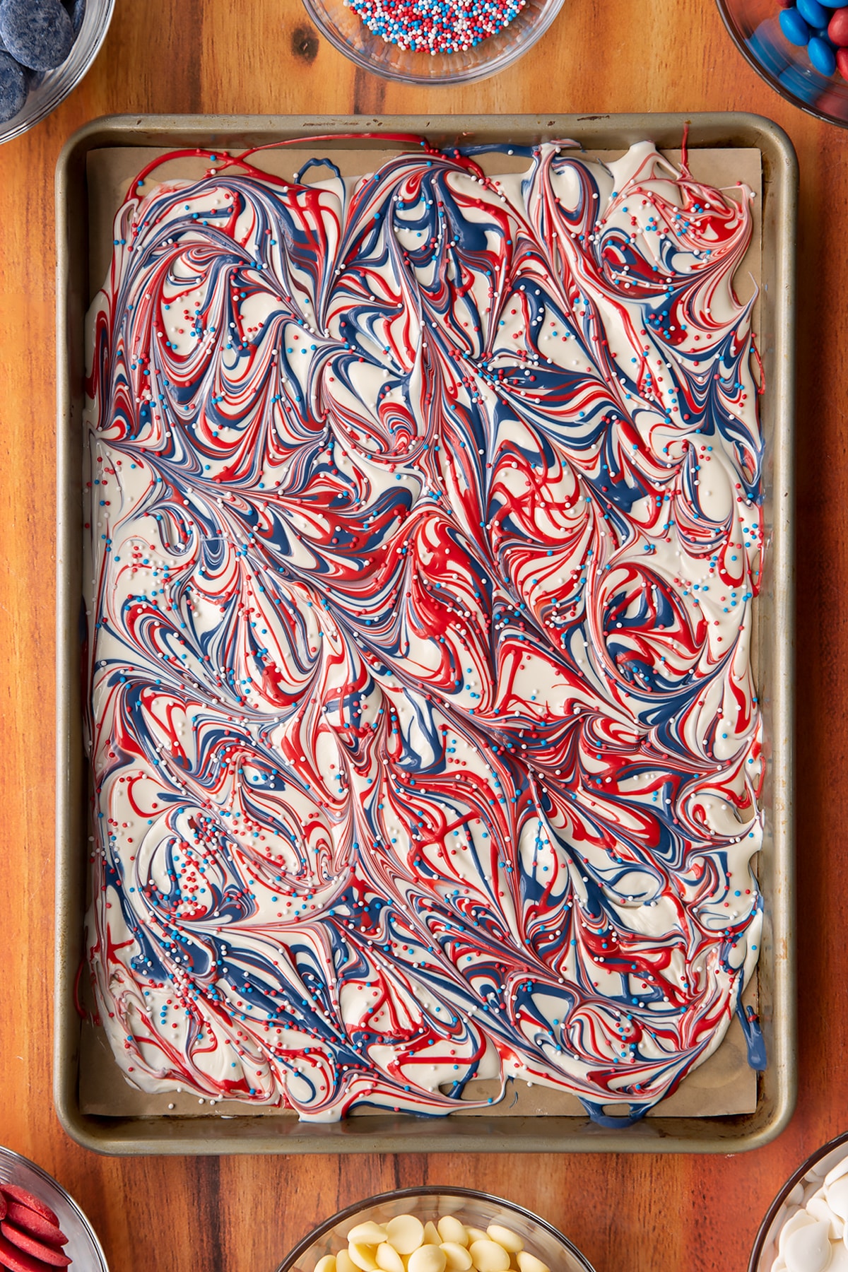 Overhead shot of the sprinkles being added to the red, white and blue bark.