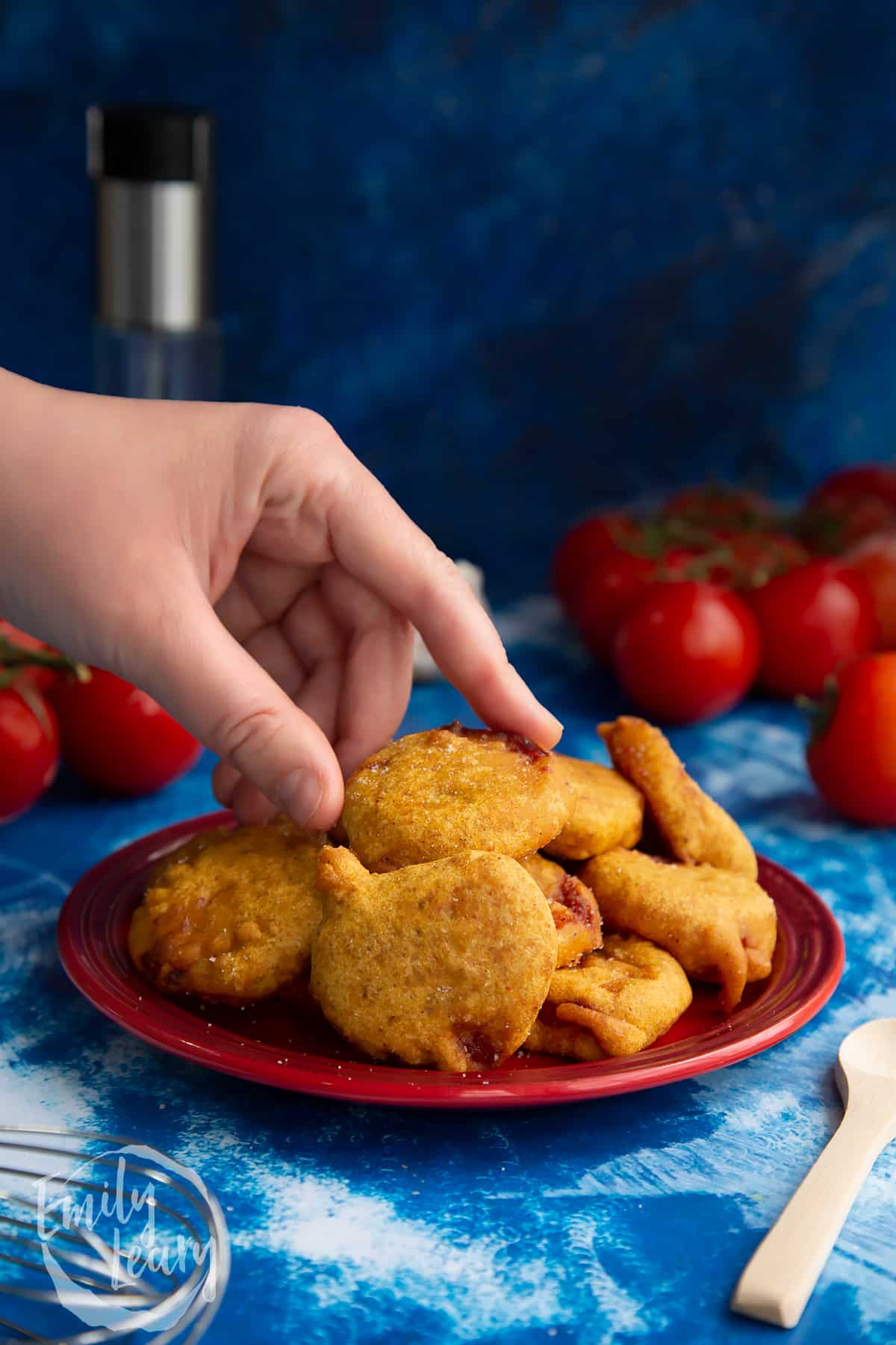 Hand reaching in to grab a tomato pakora.