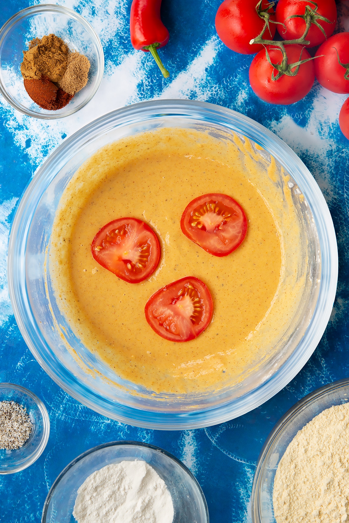Adding sliced tomatoes into the tomato pakora spice batter mixture.